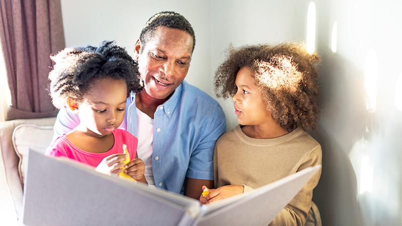 father reading to young daughters